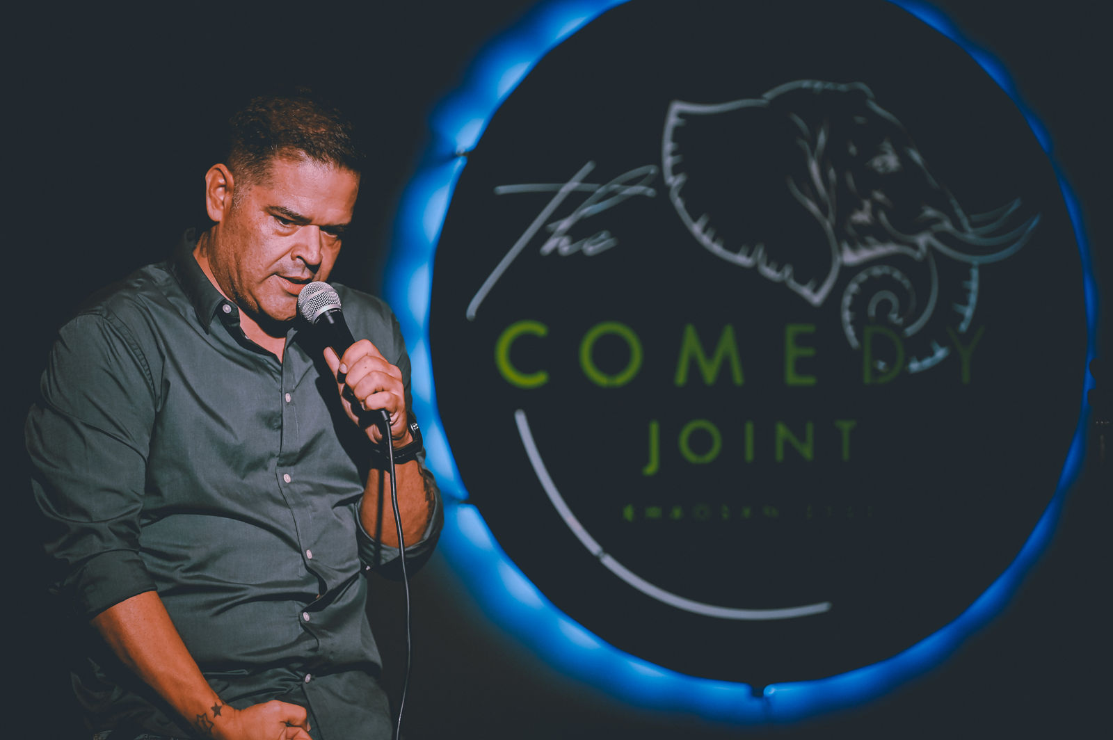 A comedian performing in front of The Comedy Joint sign