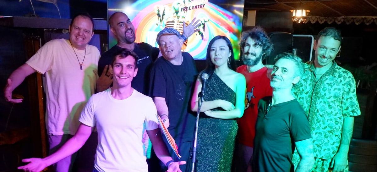 A group of comedians gathered around a microphone after a show