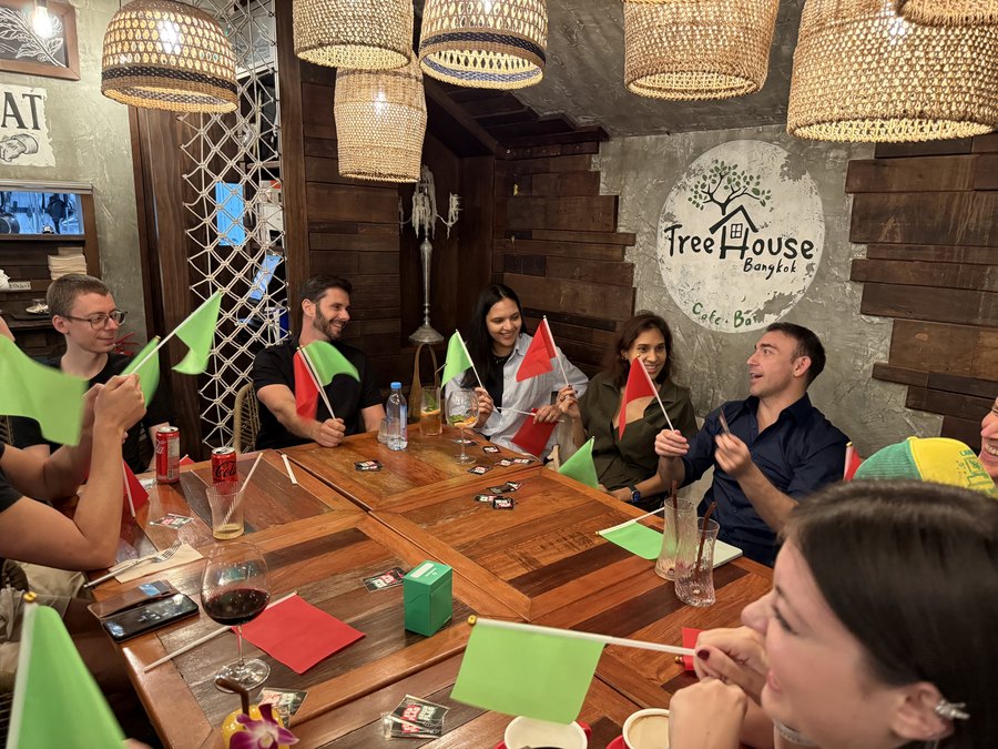Players holding red and green flags around a table at Treehouse Bangkok