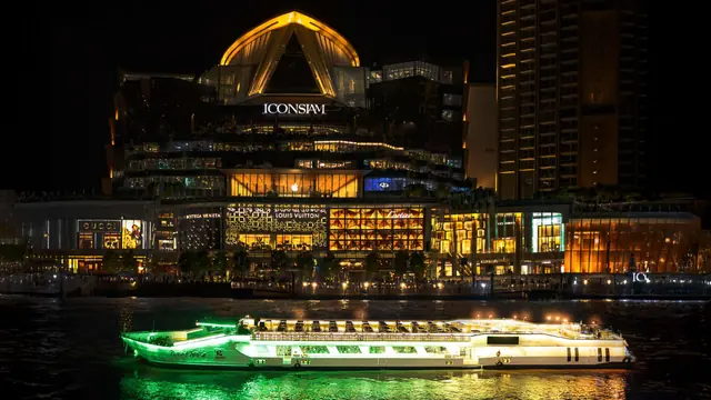 A cruise boat lit green in front of ICONSIAM