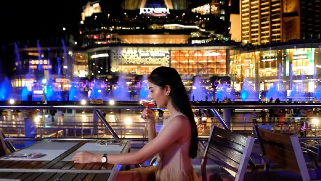A diner at a table on deck with ICONSIAM behind