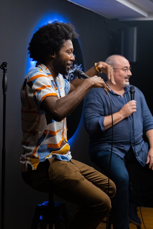 Two comedians laughing together on stage