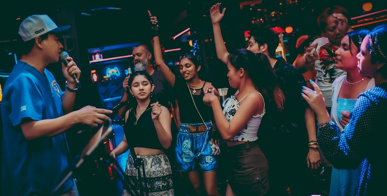 A Pub Crawls Thailand group dancing beside the host, who has a microphone, on Sukhumvit Soi 11