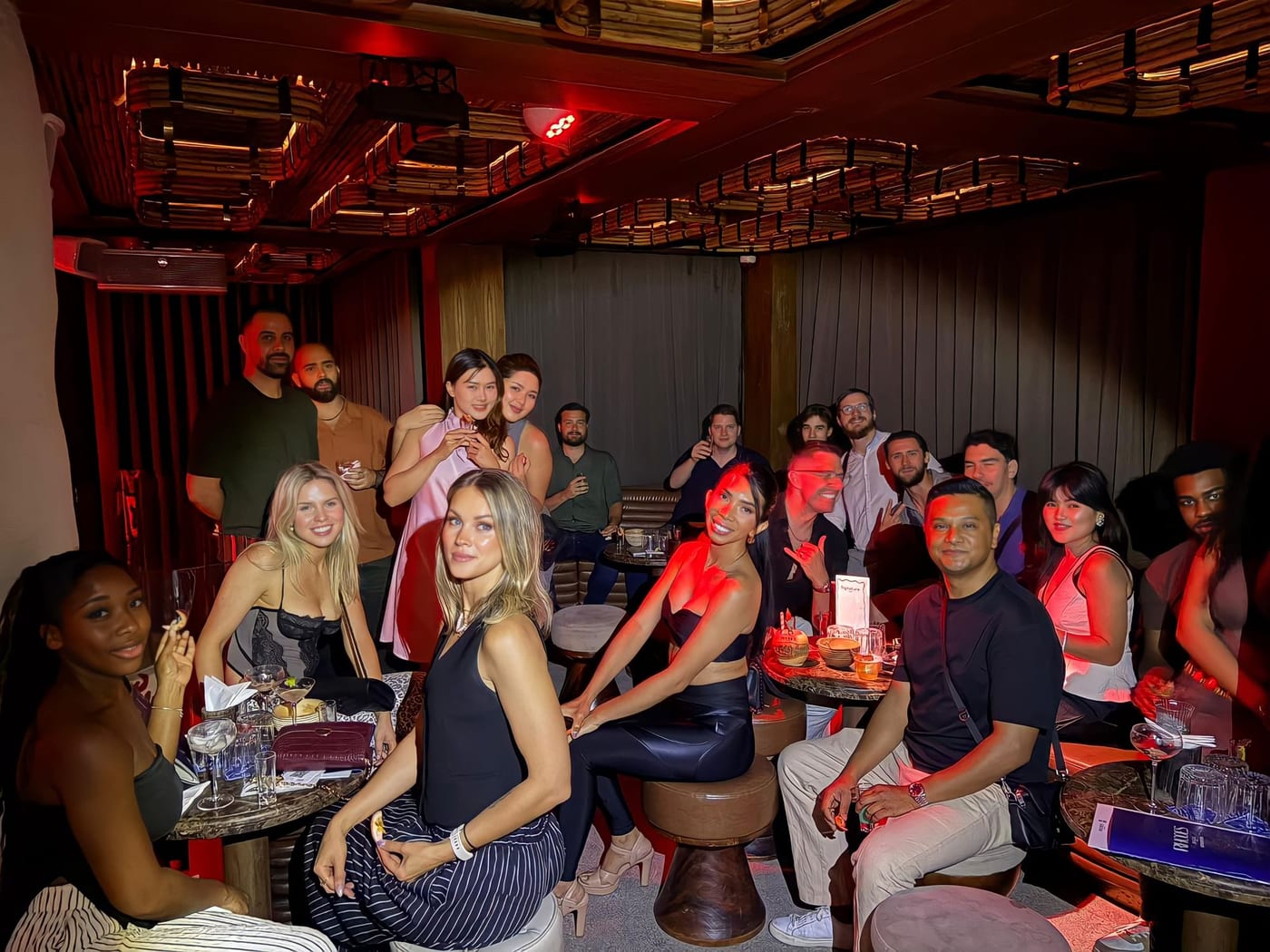 A BKK Club Crawl group seated round low tables at the first stop, a bar with a bamboo ceiling