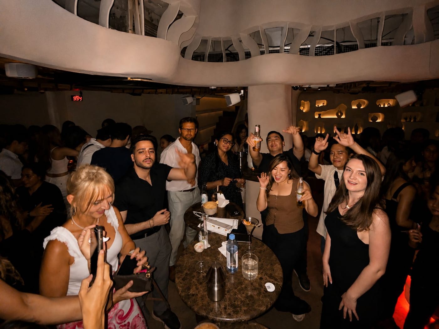 A BKK Club Crawl group raising bottles at a bar's standing tables