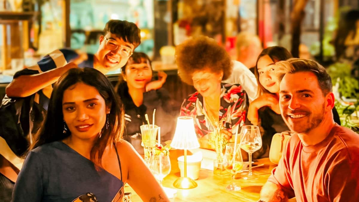 Six guests round a candlelit table at a bar in Chinatown on the sunset and speakeasy night