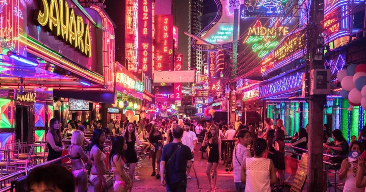 Soi Cowboy at night, neon signs on both sides and the street full of people