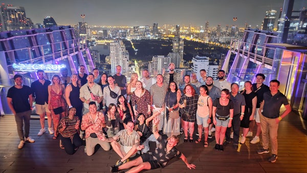 Intoxicate Bangkok's crawl group on the Spectrum rooftop at the Hyatt Regency Sukhumvit, the city lit up behind them