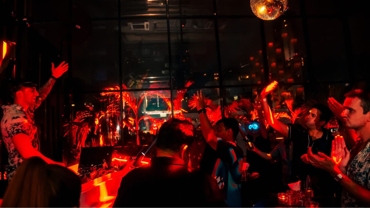 Pub Crawls Thailand's group at a Soi 11 rooftop bar lit red, arms in the air