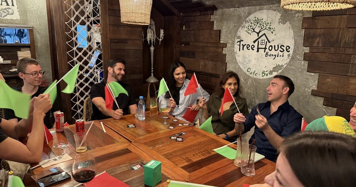 Players holding red and green flags around a table at a Crimson Cat game night, Treehouse, Sukhumvit 31